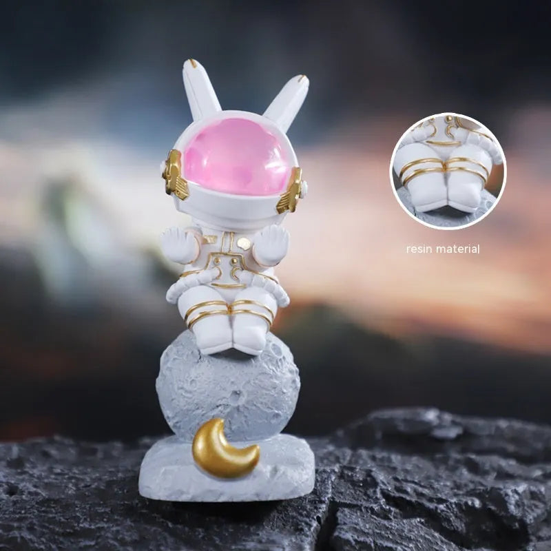 Space Rabbit resin phone stand in pink holding a smartphone on a desktop