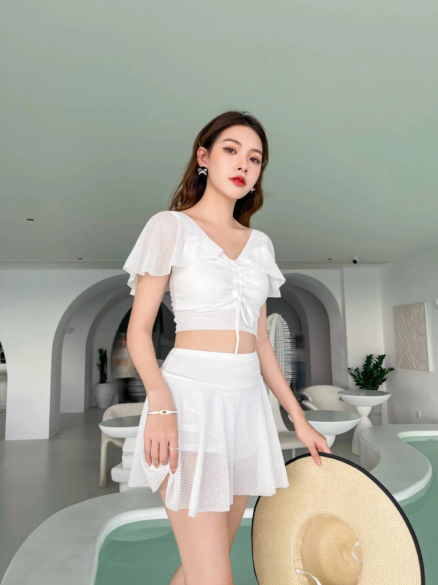 White two-piece women's swimsuit with a skirt bottom, shown alongside black and pink colour options.