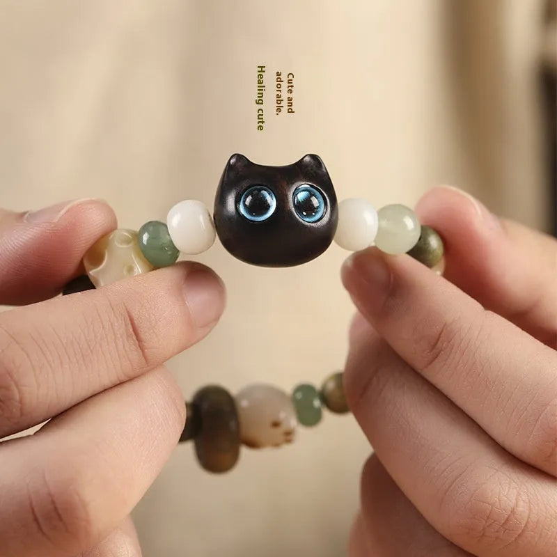 Hand-woven cat paw bracelet with a jade, bodhi seed, and ebony multi-treasure cube charm.
