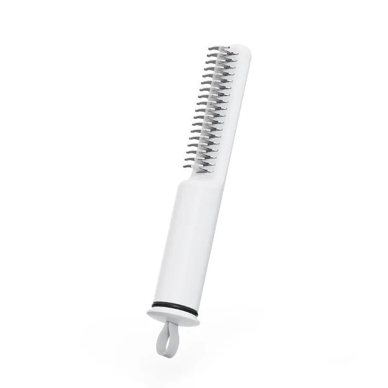 Pink and white stainless steel dog dematting comb with rake teeth on a wooden table.