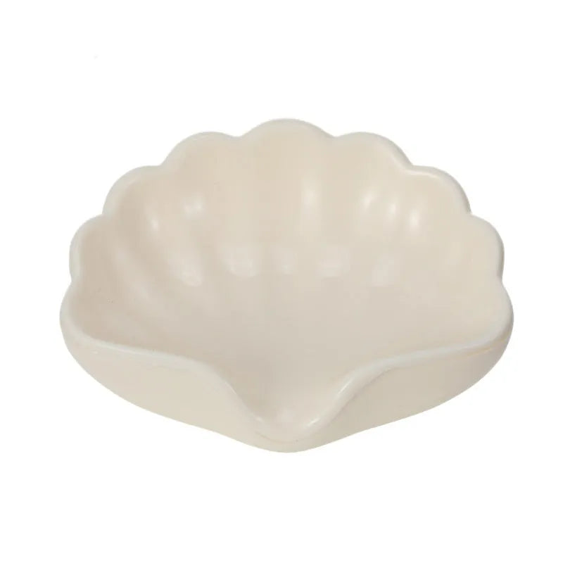 White shell-shaped plastic soap dish for bathroom countertop.