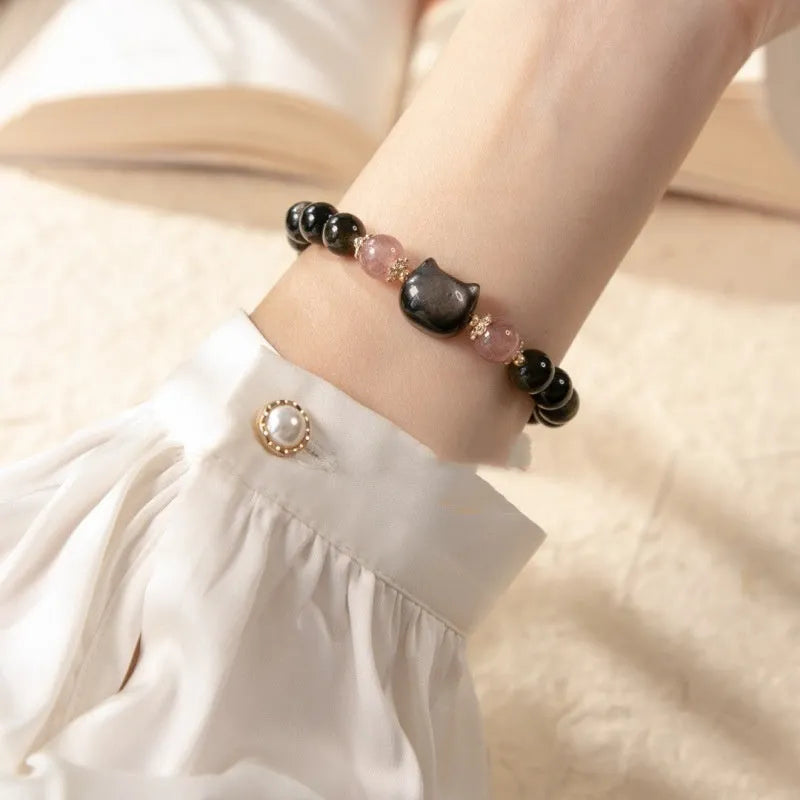 Black obsidian beaded bracelet with silver kitty cat charms on a wrist.