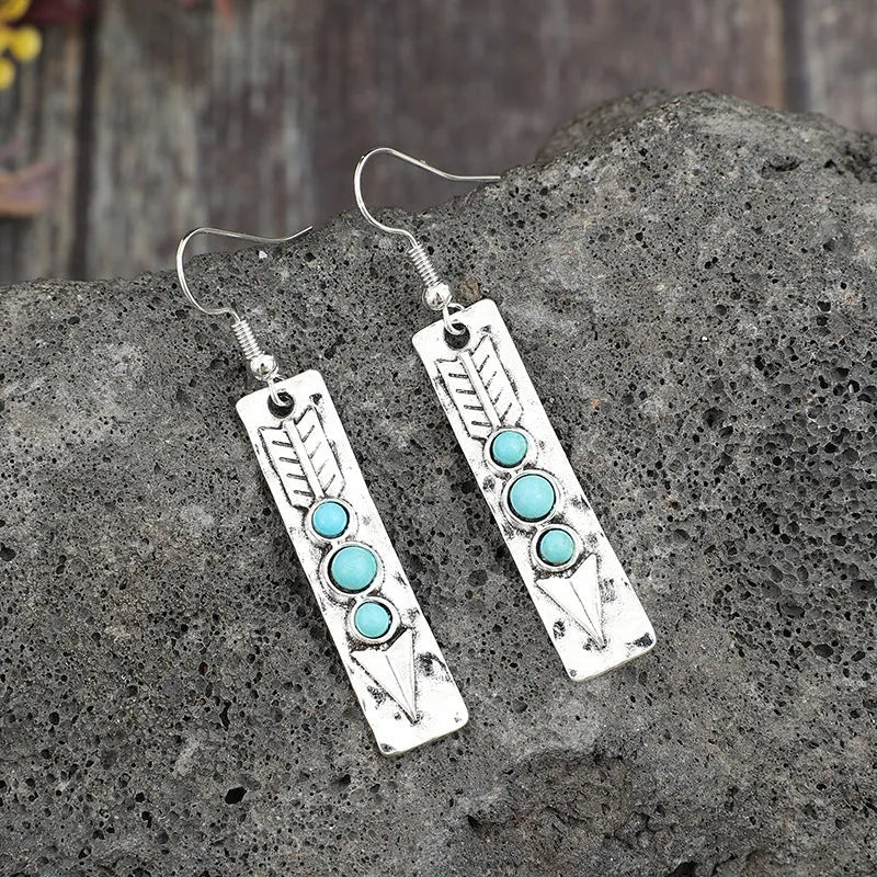 Silver geometric earrings with turquoise detail on white background