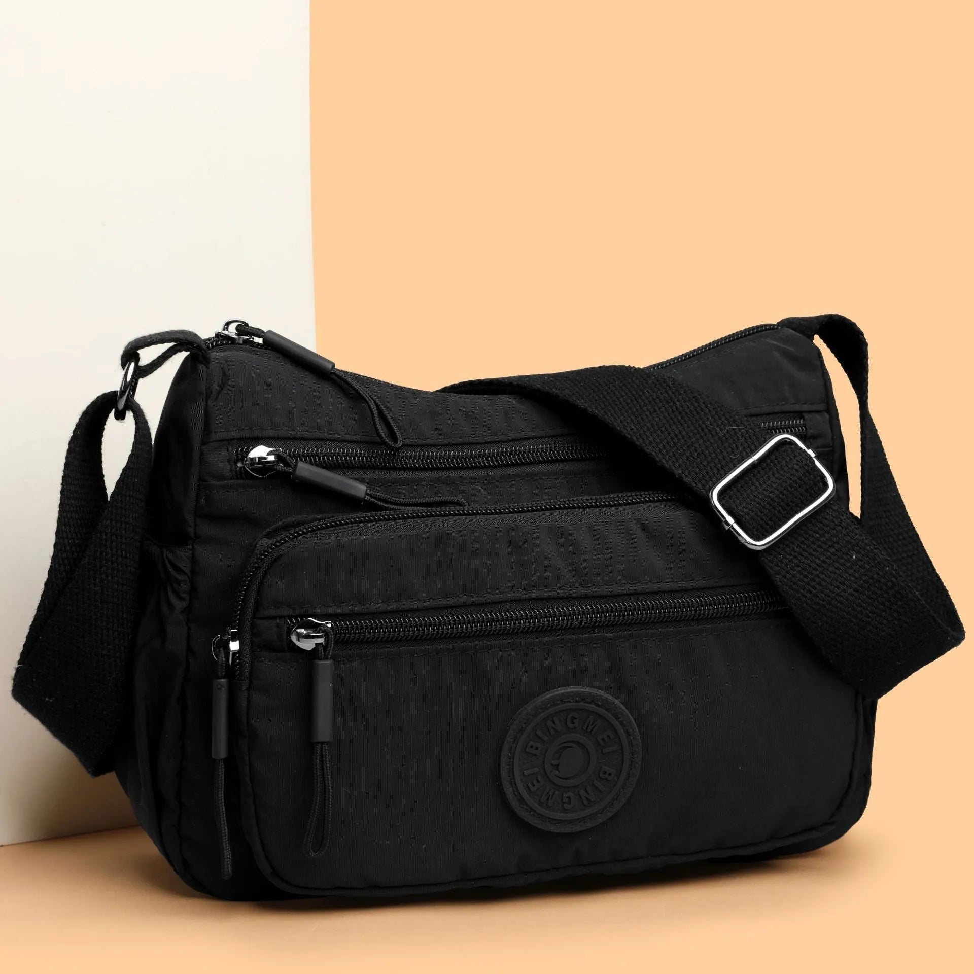 Grey water-repellent nylon crossbody bag showing front three-dimensional pocket and adjustable shoulder strap.