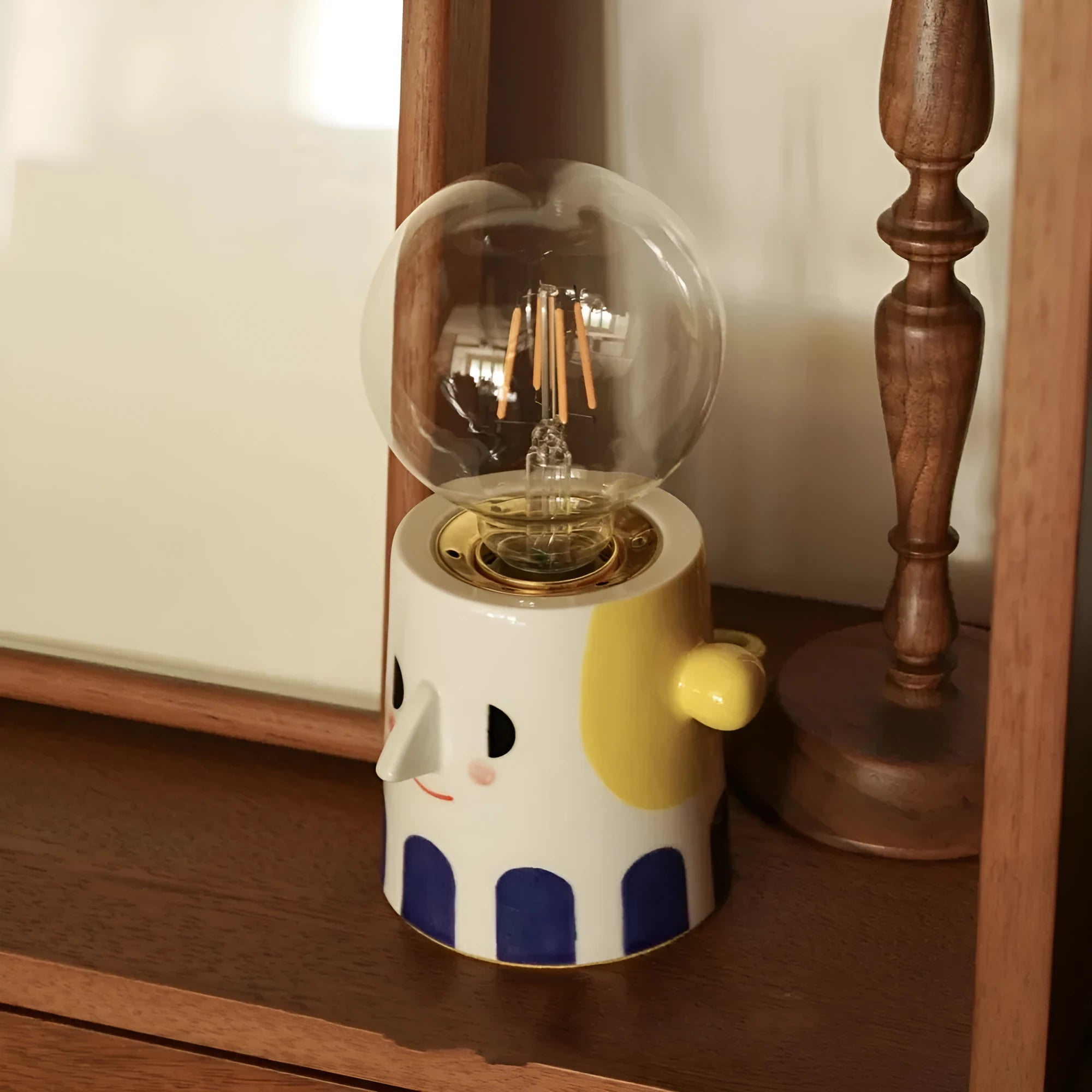 Handmade white ceramic table lamp with a creative ball headlight design on a wooden surface.