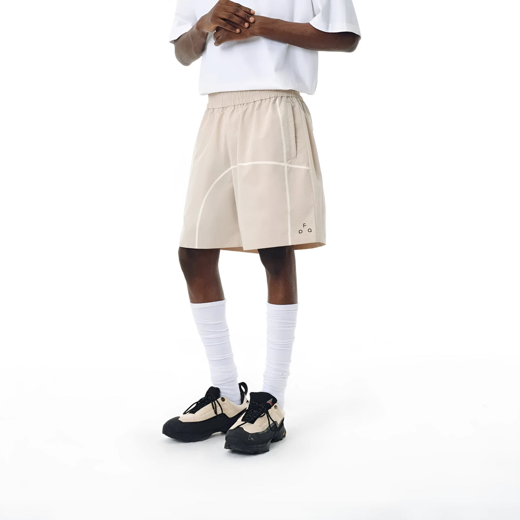 High-elasticity polyester drawstring shorts in apricot colour on a beach background.