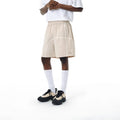High-elasticity polyester drawstring shorts in apricot colour on a beach background.