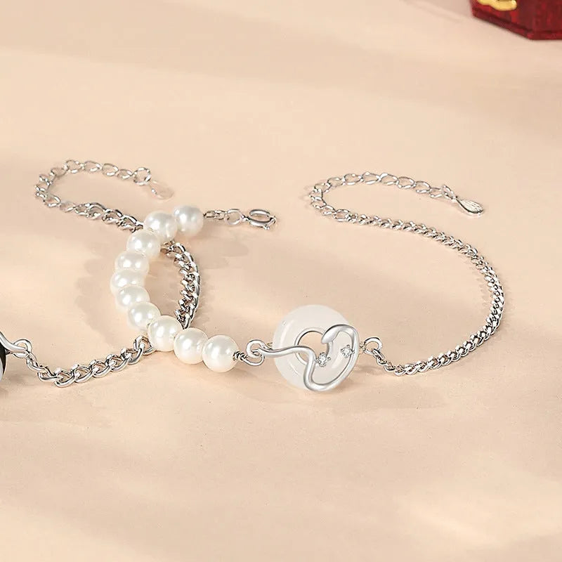 A New Chinese style 925 sterling silver couple's bracelet with a safe buckle, snake motif, and a central obsidian pearl.