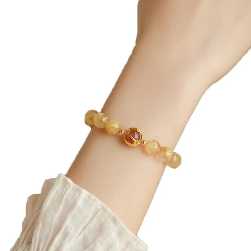 Citrine and gold rutilated quartz bracelet with diamond-cut beads in 6mm or 8mm size on a wrist.