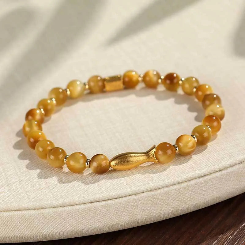 Close-up of a women's bracelet with small fish-shaped Tiger Eye stone beads in yellow, red, or gold colours.