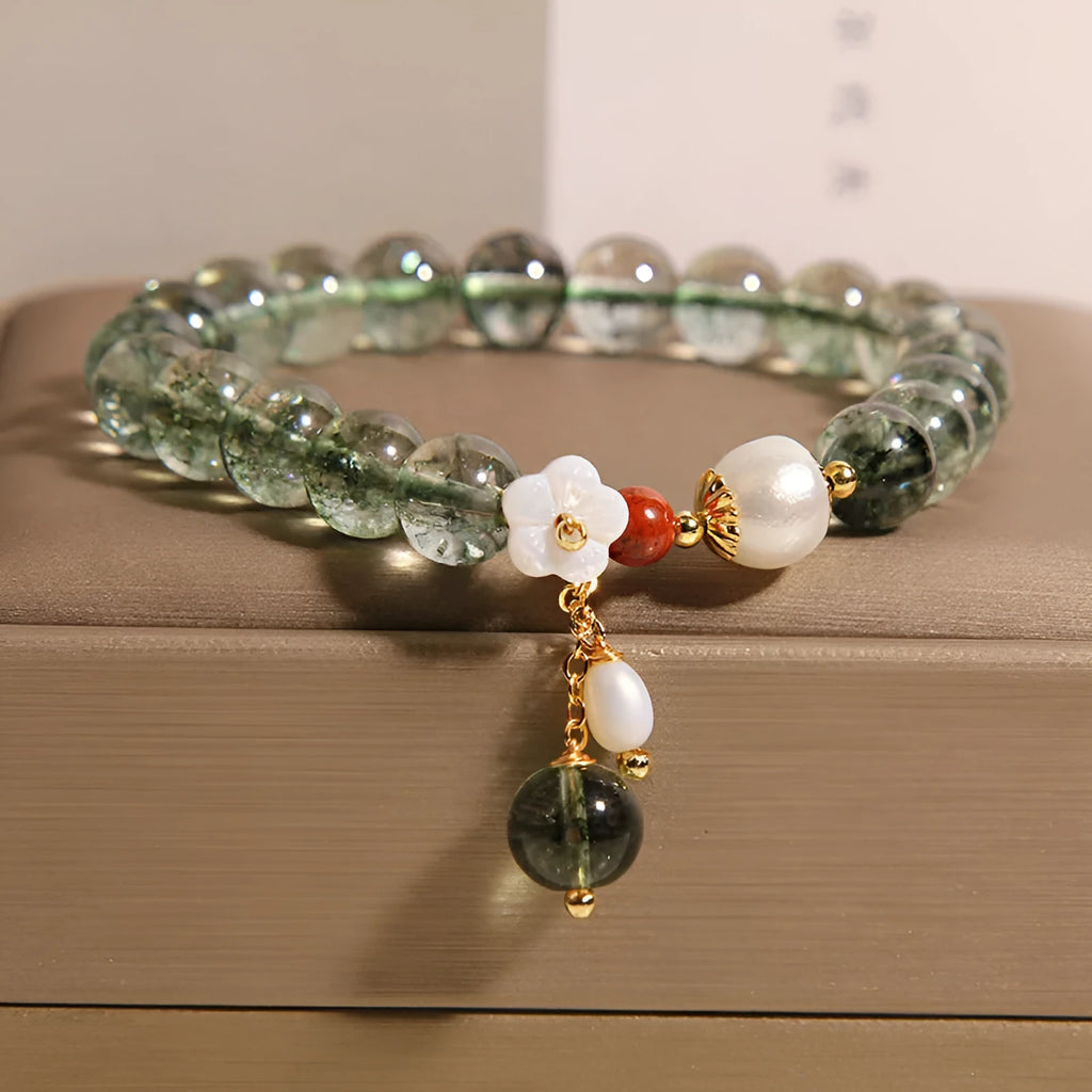 Green phantom quartz crystal bracelet with shell flower charm on a woman's wrist
