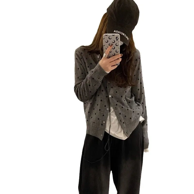 Women's grey loose-fit knitted cardigan with a crocheted flower on the front.
