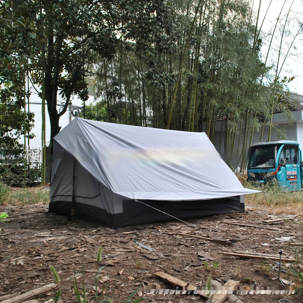 Brown ultralight A-frame hiking tent pitched with hiking poles in an outdoor setting