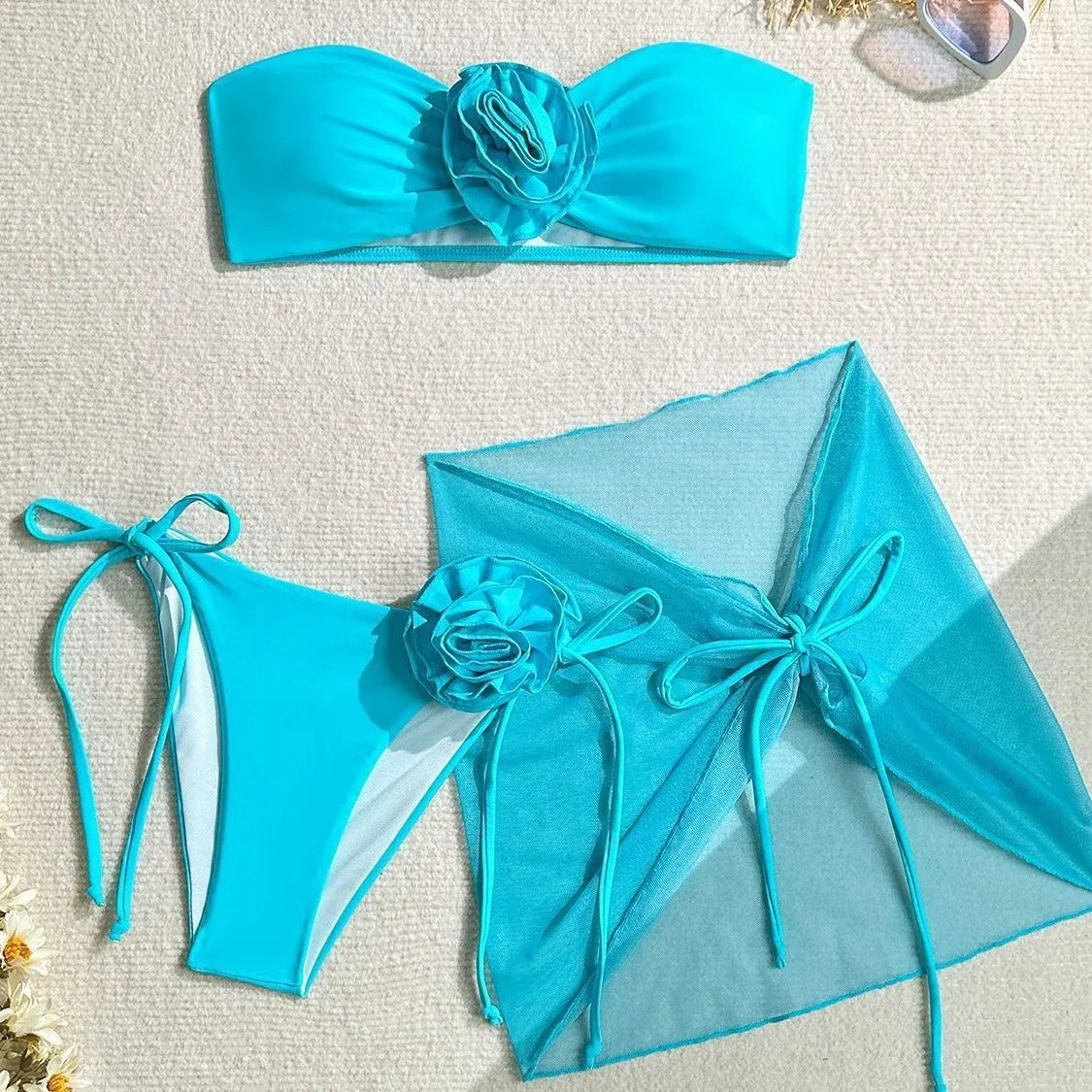 Women's blue tube top swimsuit with a large tied flower, matching pants and skirt.