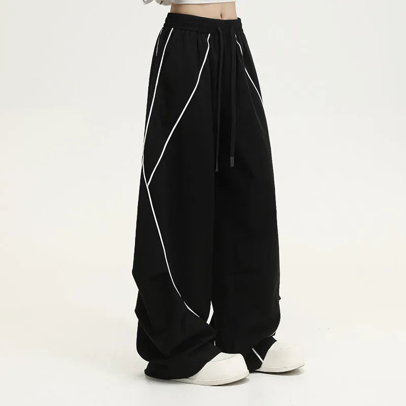 Black striped pleated wide-leg hip hop trousers laid flat, showing loose fit and mid waist.