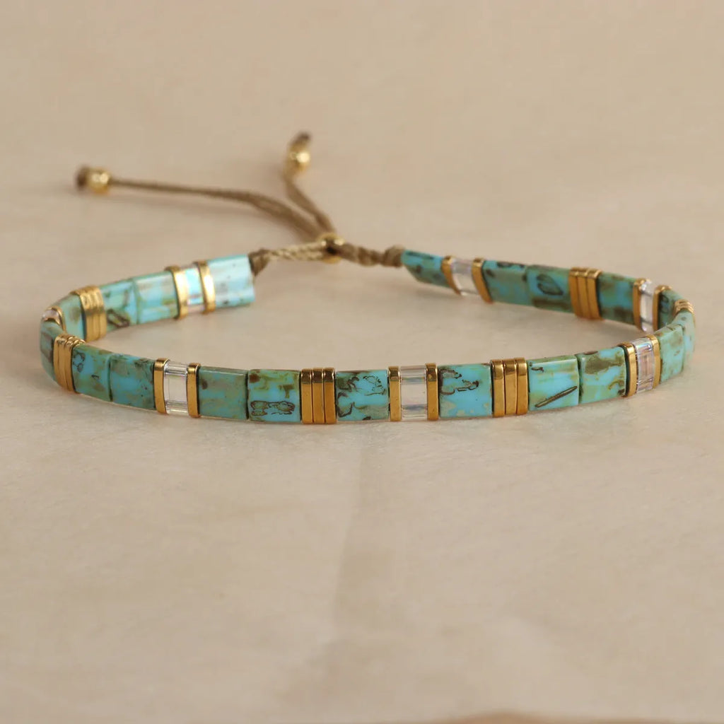Geometric round glass bead bracelet in five colour options on a wrist.