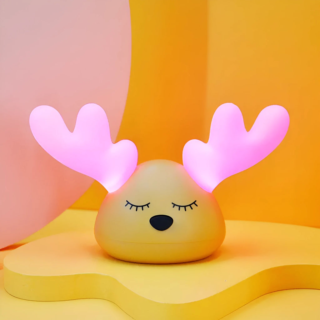 Children bedside Christmas deer night light with colour-changing LED and soft silicone shade on a table
