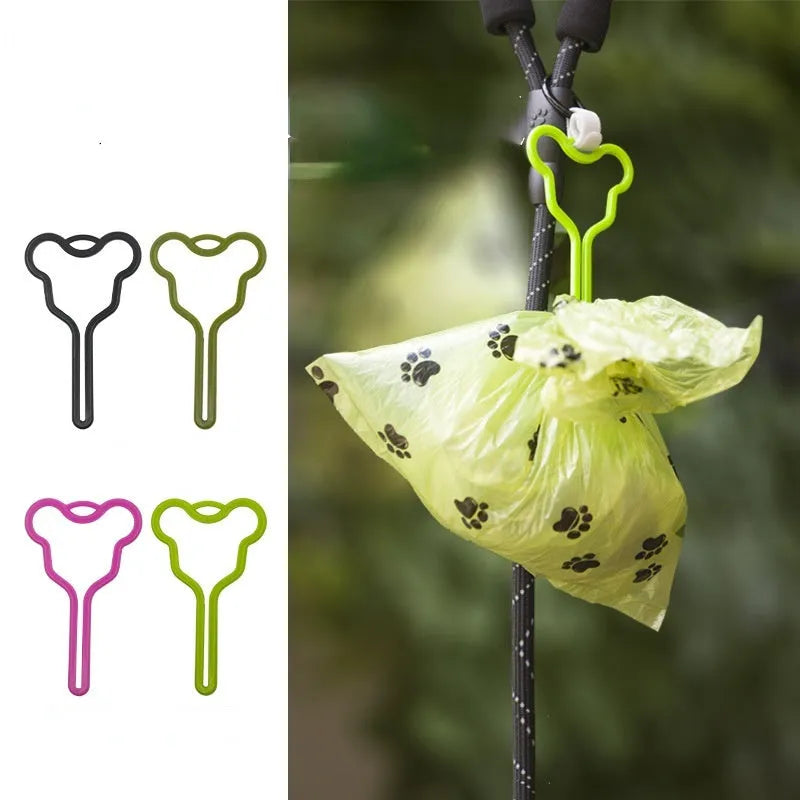 A hands-free dog poop bag holder with a fixed metal clip and a black Velcro strap for leash attachment.