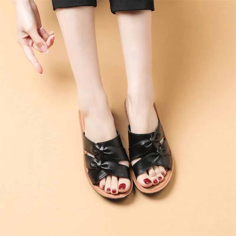 Beige cowhide leather slippers for women with a soft sole, shown from the side.