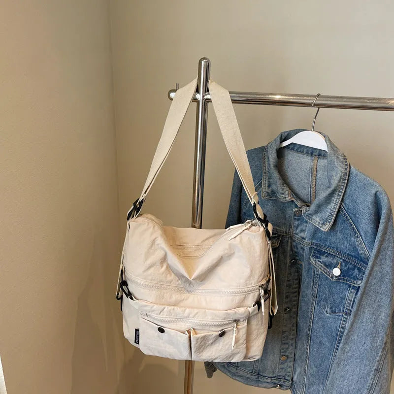A square-shaped nylon crossbody bag for women in a choice of colours, showing shoulder straps and external pocket.