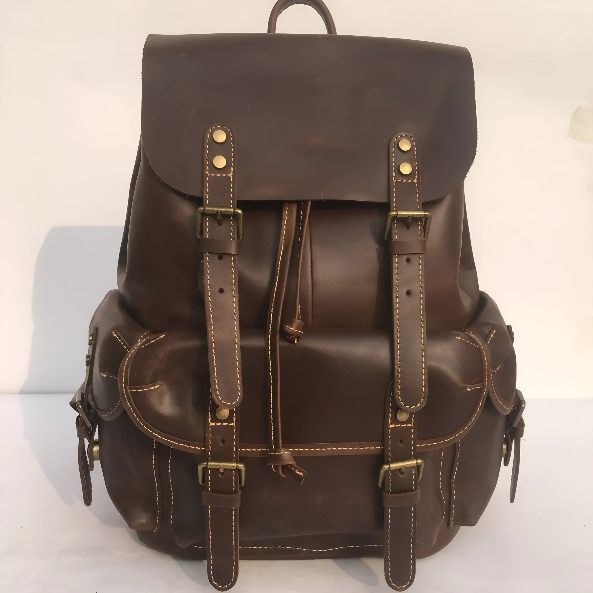 Brown men's leather backpack showing genuine cowhide material and integrated air pillow shoulder straps.