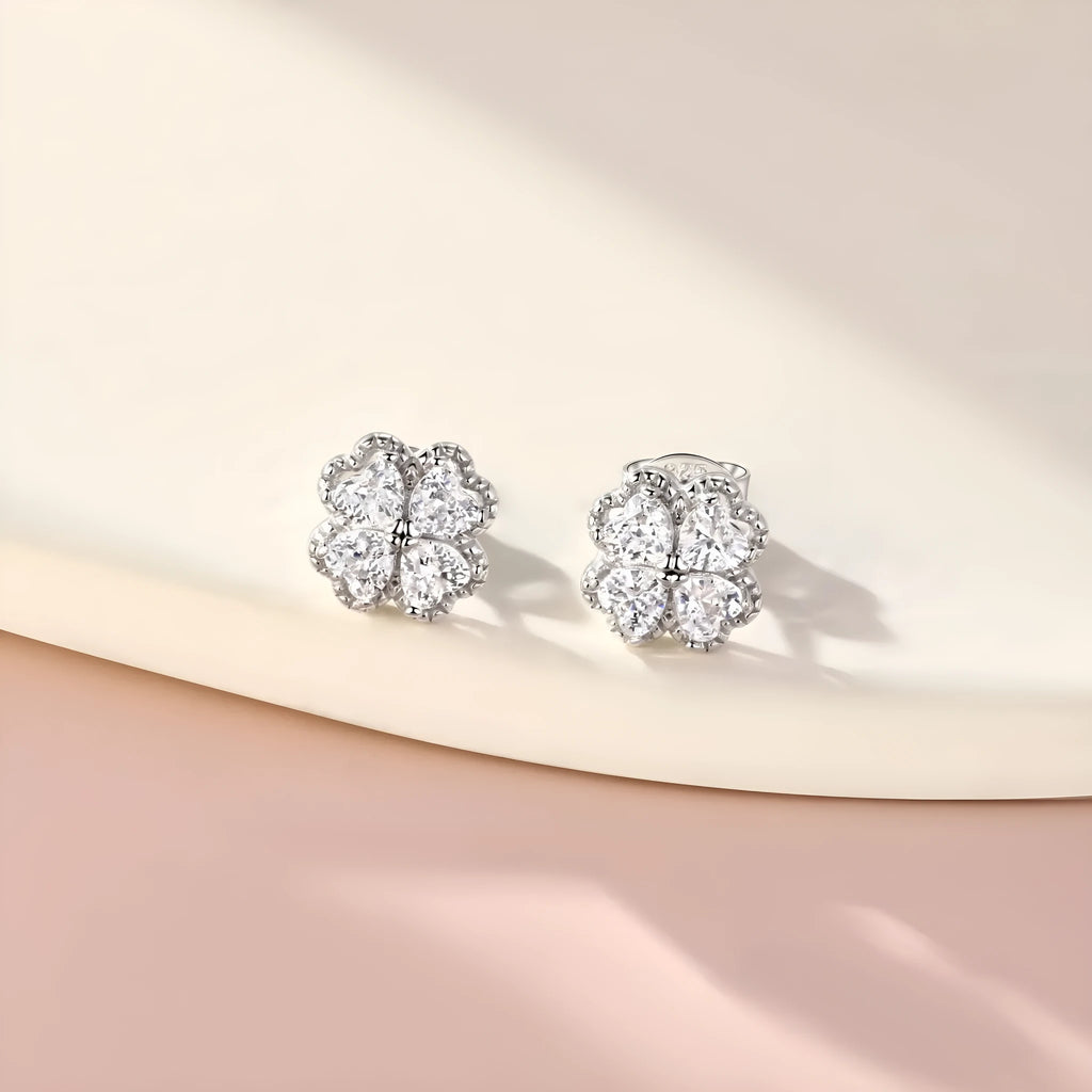 Close-up of women's white gold coloured heart shaped earrings with a four-leaf clover design, made from 925 silver and inlaid zircon stones.