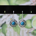 Handmade silver and turquoise ethnic earrings with geometric flower disk and traditional patterns.