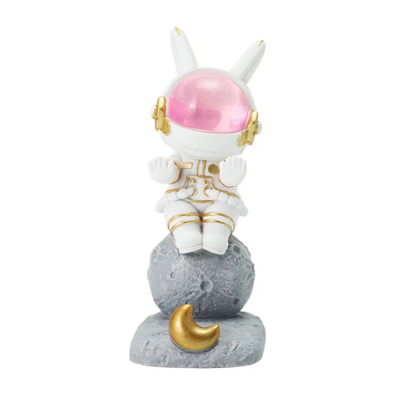 Space Rabbit resin phone stand in pink holding a smartphone on a desktop