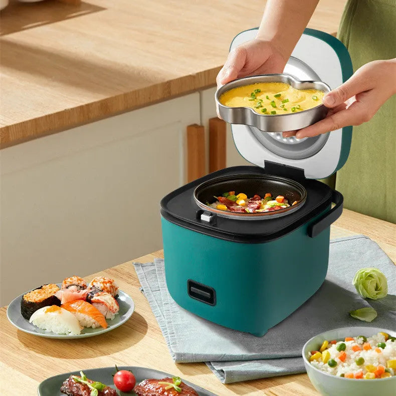 Green 1.2L mini rice cooker with metal body, button controls, and steaming plate on a worktop.