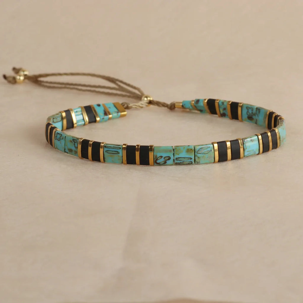 Geometric round glass bead bracelet in five colour options on a wrist.