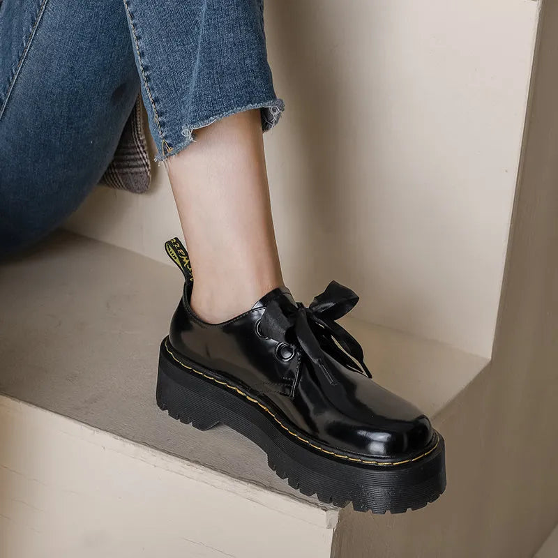 Black women's lace-up shoes with a thick sole, ribbon detail, and cross straps.