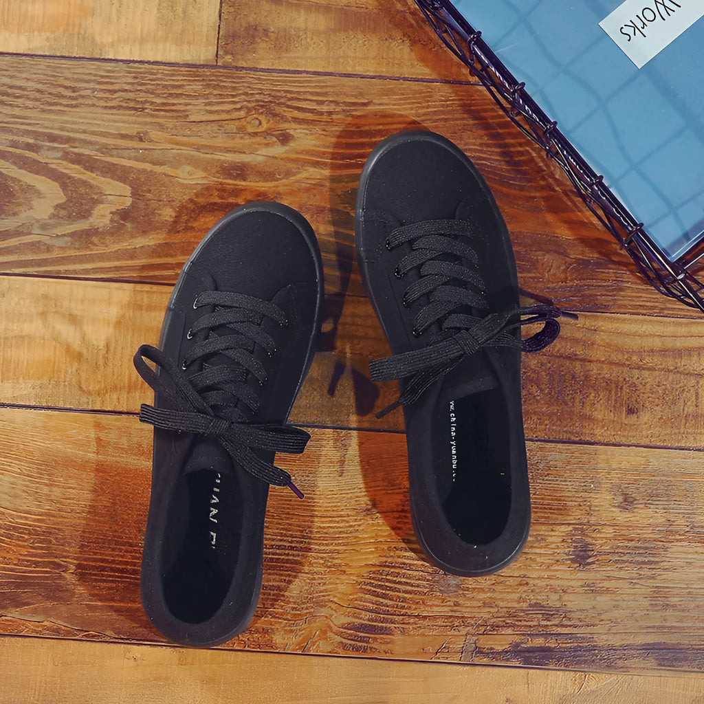 All black women's canvas lace-up work shoes with flat rubber soles.