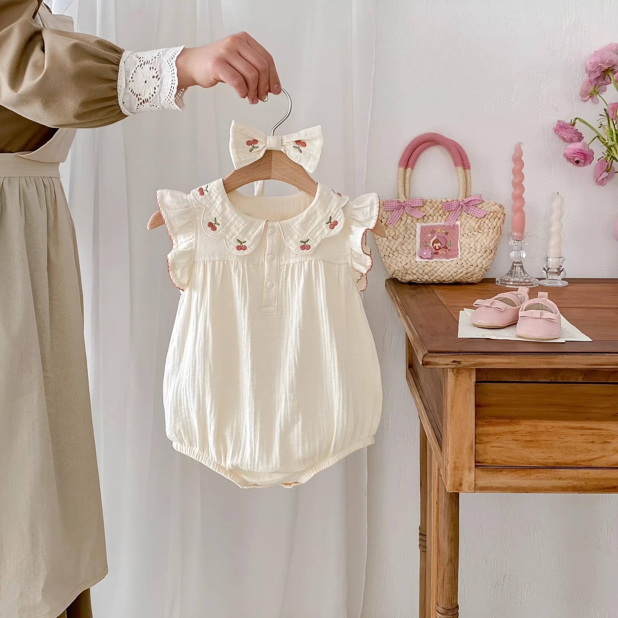 Apricot cotton double breasted sleeveless baby jumpsuit with matching hair band on white background