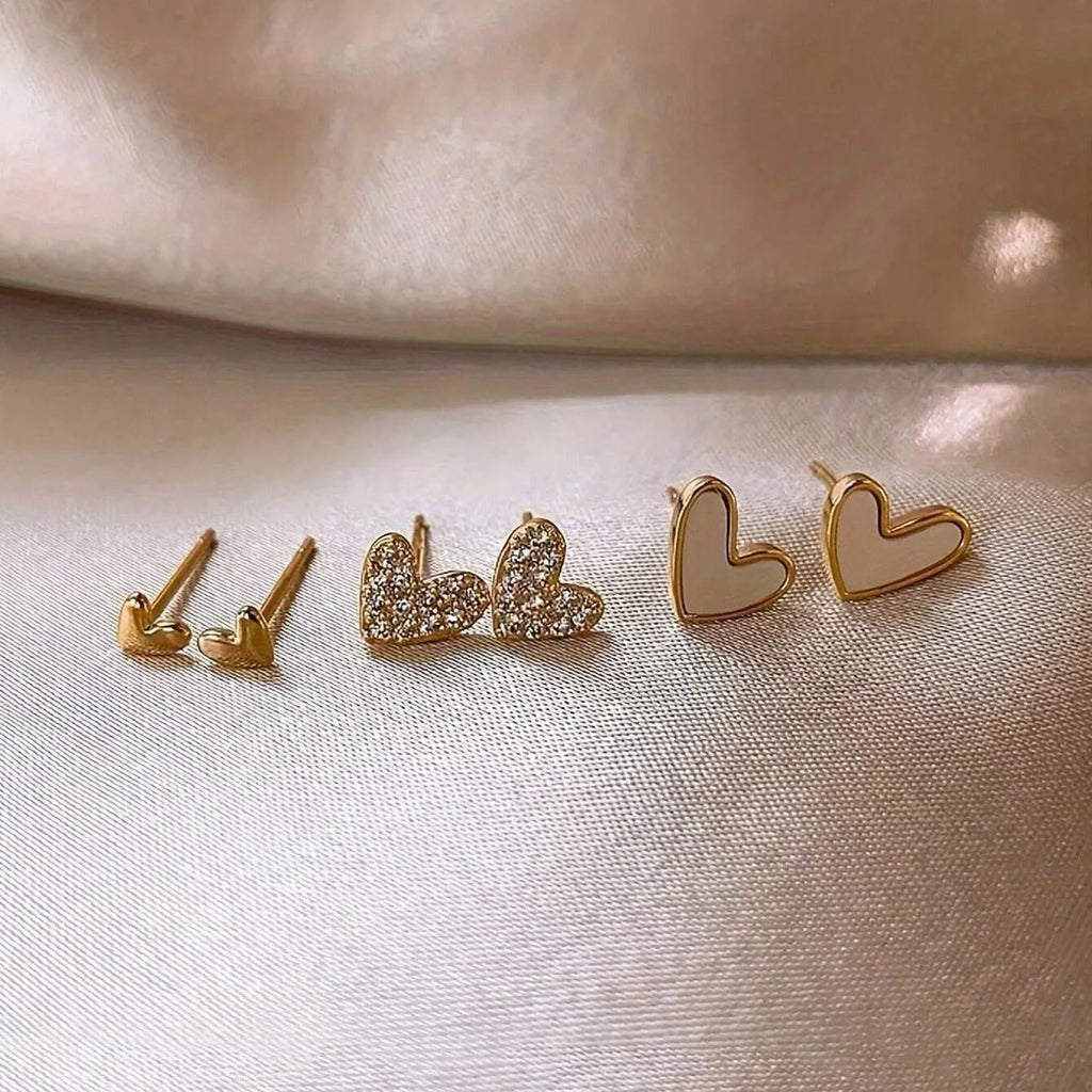 Three pairs of women's heart-shaped alloy earrings in gold, black, black and white, and pink colours