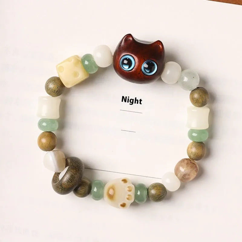 Hand-woven cat paw bracelet with a jade, bodhi seed, and ebony multi-treasure cube charm.