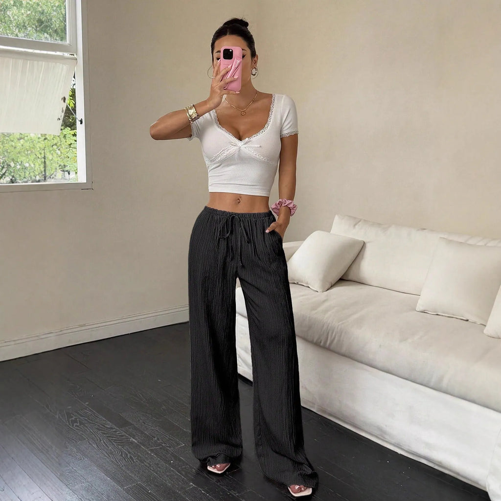 Women's black wide-leg trousers with a front lace-up waist detail on a mannequin.