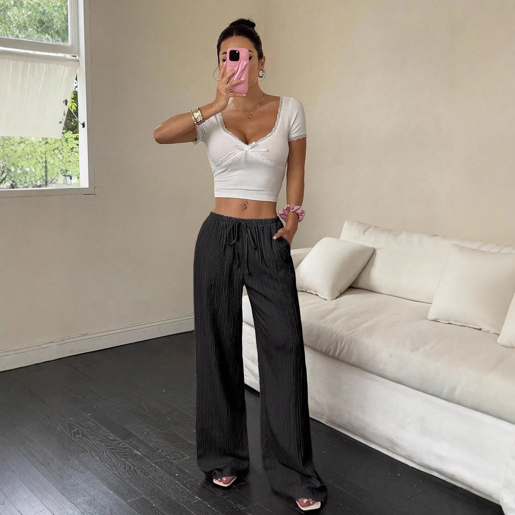 Women's black wide-leg trousers with a front lace-up waist detail on a mannequin.