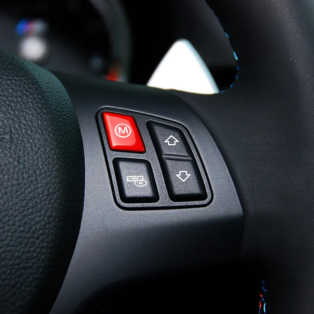 Pair of red and blue BMW M1 M2 steering wheel mode buttons on a dark background.