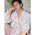 Pink embossed floral pattern long sleeve shirt laid flat, showing loose fit and textured design.