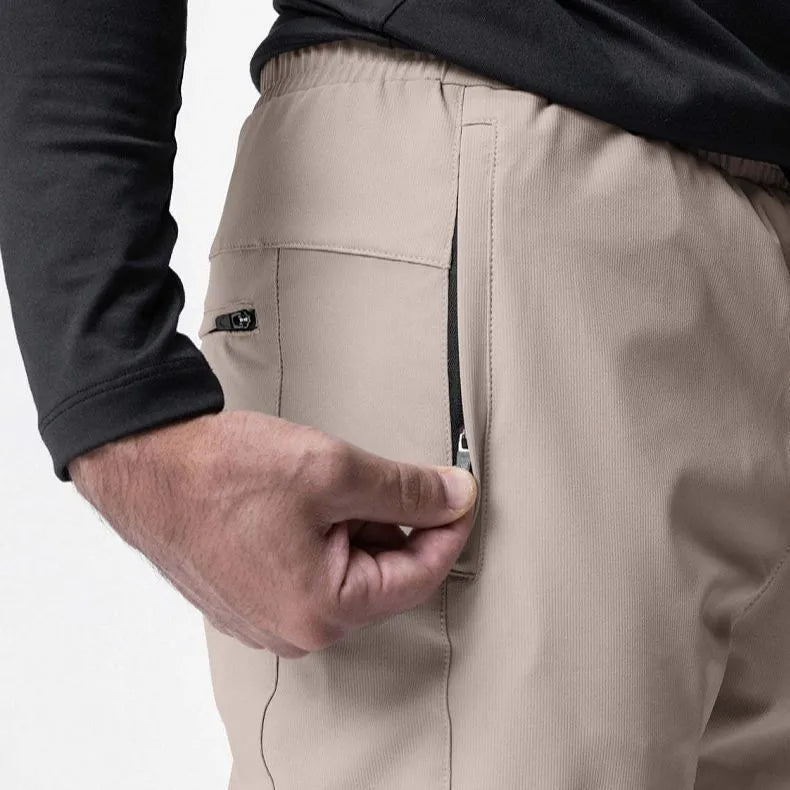 Man wearing loose grey running trousers with tied ankles, made from quick-dry polyester fabric.