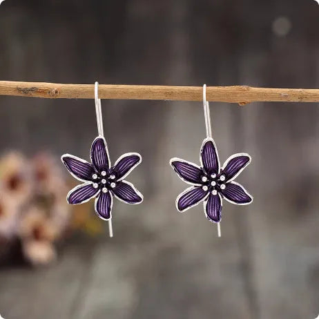 A pair of purple flower-shaped alloy stud earrings with a simple post back, shown against a plain background.
