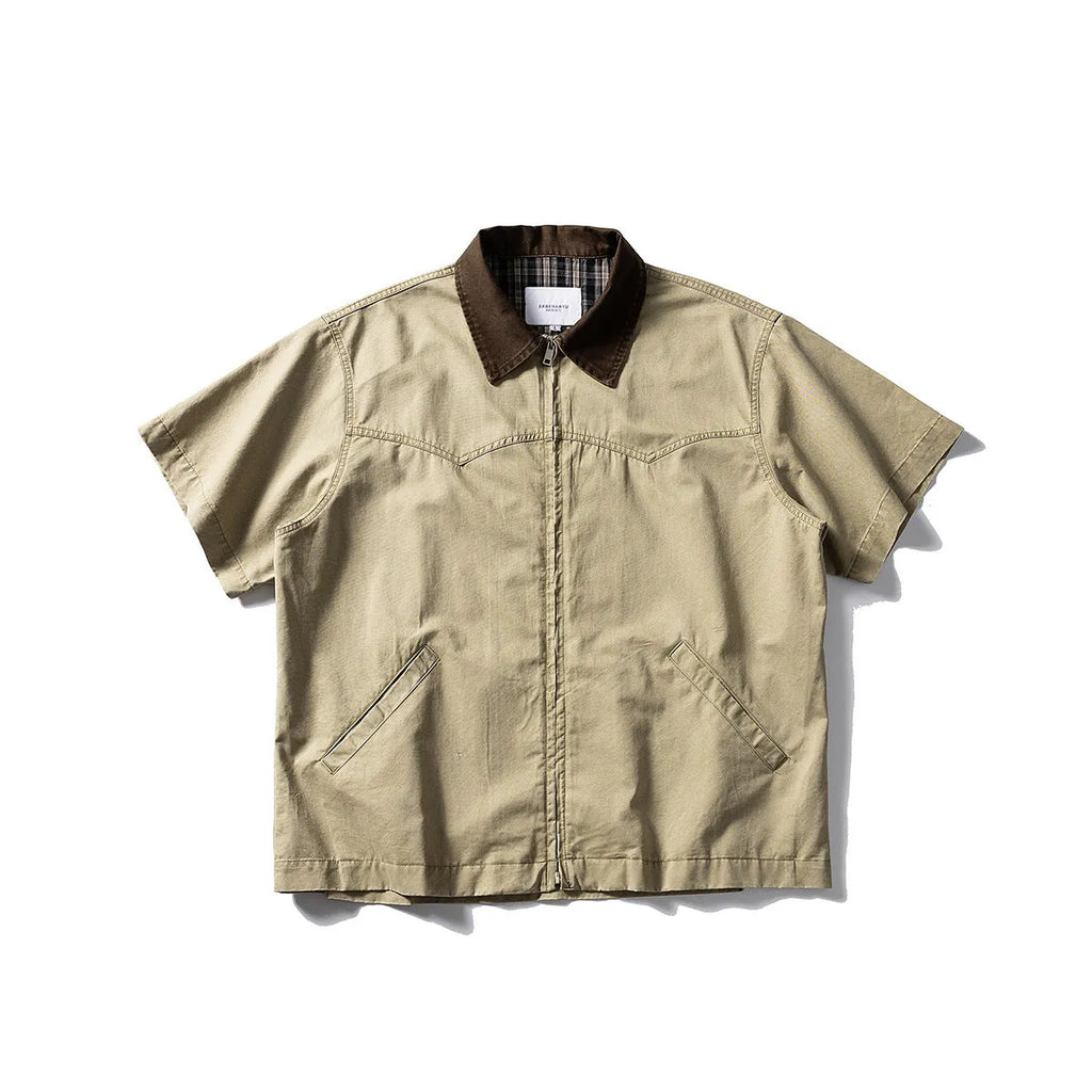 A khaki-coloured, short-sleeved overalls shirt with a loose cardigan style on a hanger.