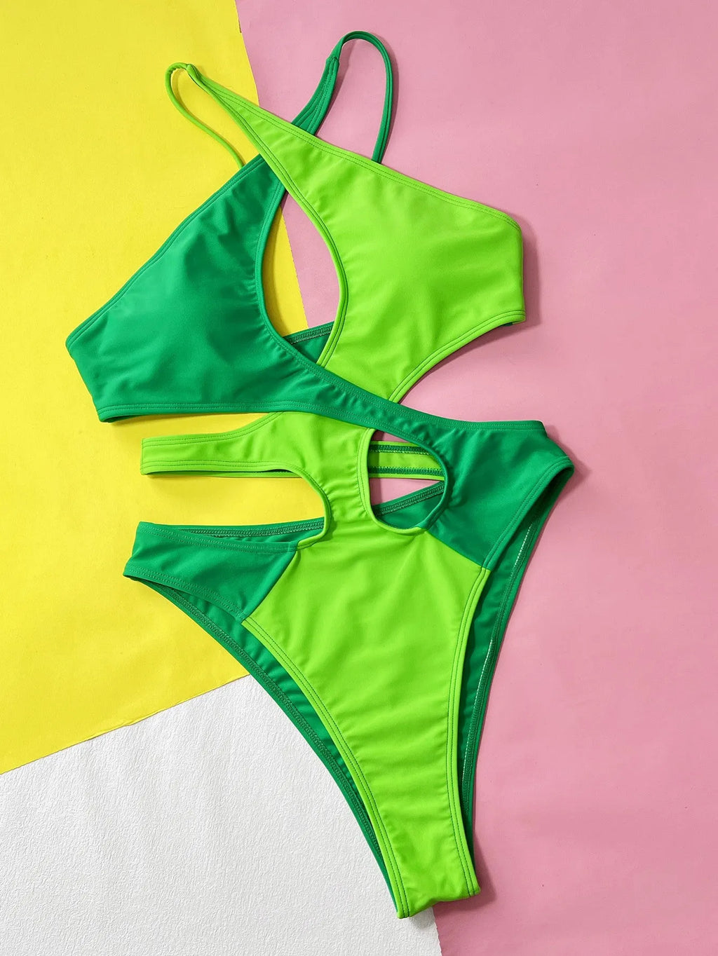 Green women's one-piece swimsuit with hollow contrast detail on a mannequin.