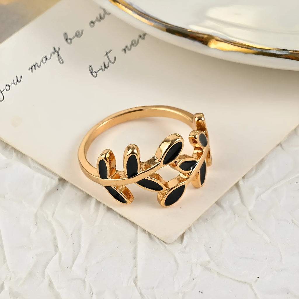 Gold-coloured acrylic ring with a geometric leaf and floral design on a white background.
