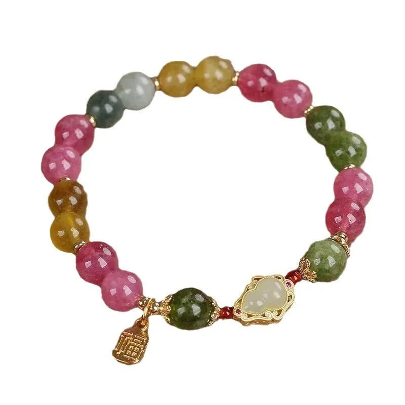 Women's bracelet with colourful tourmaline gourd blessing charm and floral clasp on a mixed material chain.