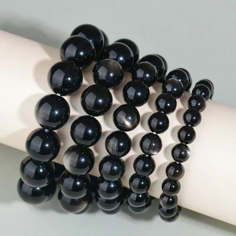 Hand-woven obsidian bracelet with round crystal beads in black stone variations including rainbow eye obsidian