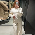 Women's black polar fleece suit set with long sleeve pleated top and wide leg trousers on a hanger.