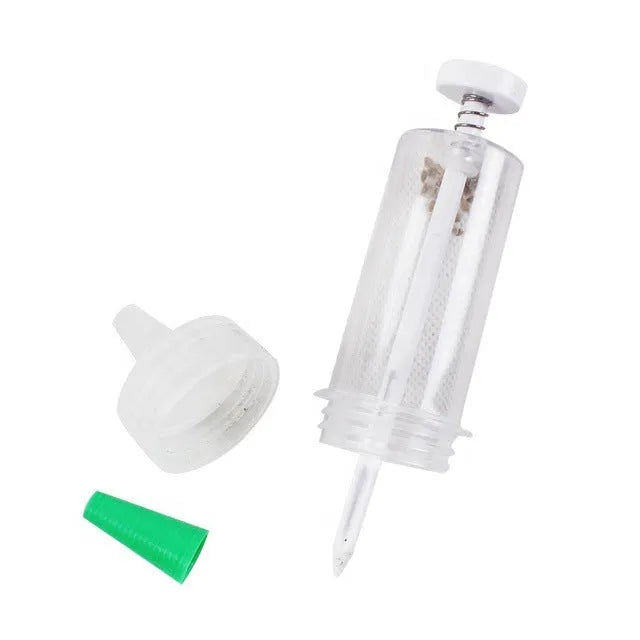A white plastic mini seeder tool measuring 12cm long, used for planting seeds in pots and trays.