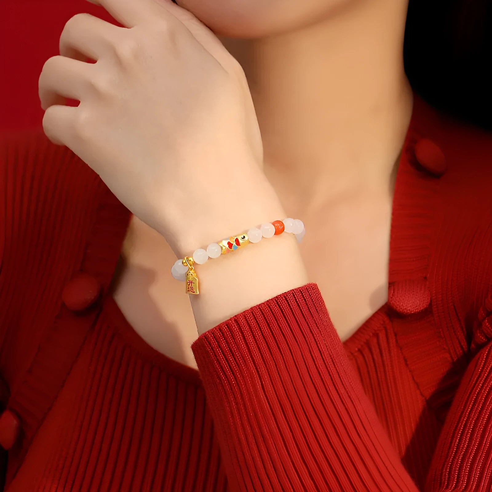 Close-up of a sterling silver bracelet with a blue and orange enamel koi fish design and a green Hetian jade stone.