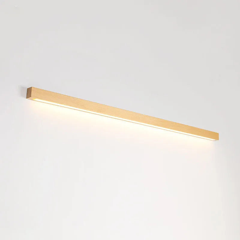 Slim, long walnut-coloured wooden strip wall lamp mounted on a plain wall.